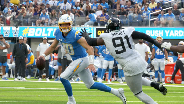 Sep 25, 2022; Inglewood, California, USA; Los Angeles Chargers quarterback Justin Herbert (10) runs the ball under pressure from Jacksonville Jaguars defensive end Dawuane Smoot (91) in the third quarter at SoFi Stadium. Mandatory Credit: Kirby Lee-USA TODAY Sports